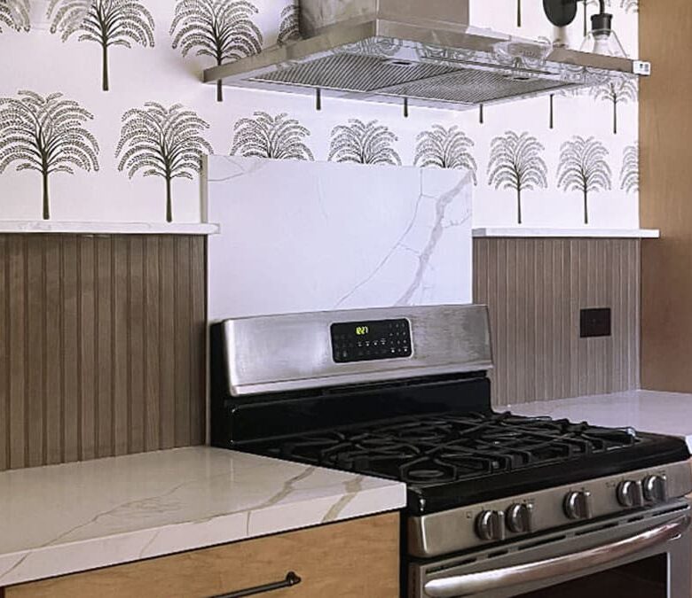 Modern kitchen retreat with wood cabinetry, quartz counters, palm wallpaper, and stainless steel range
