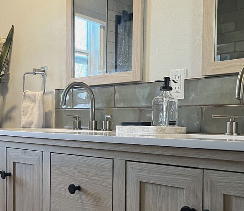 Refined natural bath design with wood vanity, dual sinks, brushed nickel fixtures, and soft green tile backsplash
