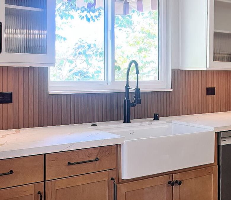 Wood kitchen reimagined with natural wood cabinetry, farmhouse sink, quartz counters, and fluted glass upper cabinets